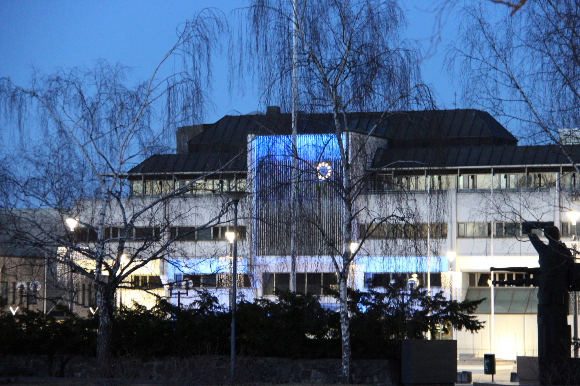 Lappeenrannan kaupungintalo iltavalaistuksessa puiden takana.